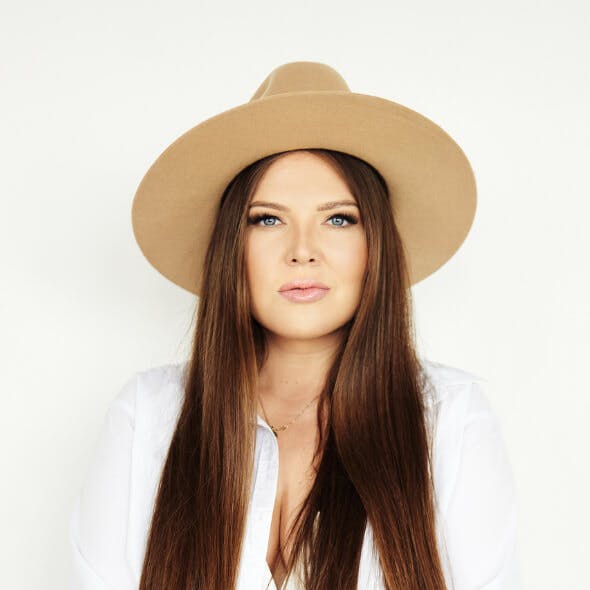 Na zdjęciu znajduje się Beata - jedna z właścicielek Agencji Marketingowej Detalle. Beata ma na sobie brązowy kapelusz i białą koszulę.